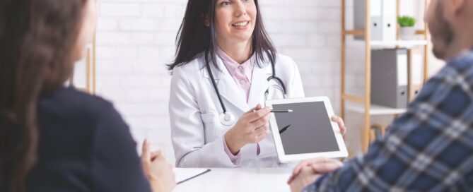 Doctor showing test results on digital tablet to married patients