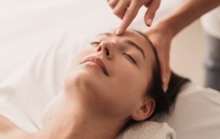 Acupuncturist pressing point on forehead of woman