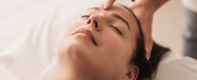 Acupuncturist pressing point on forehead of woman