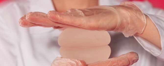 Close-up of a woman hands in transparent gloves holding silicone round breast implants